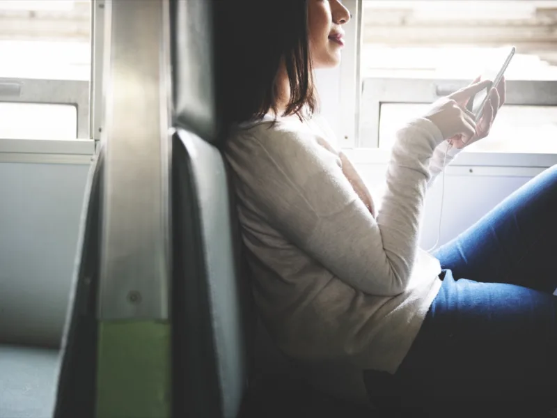 A passenger on a jeepney waits for a web page to load on an Android phone, the screen still mostly blank.